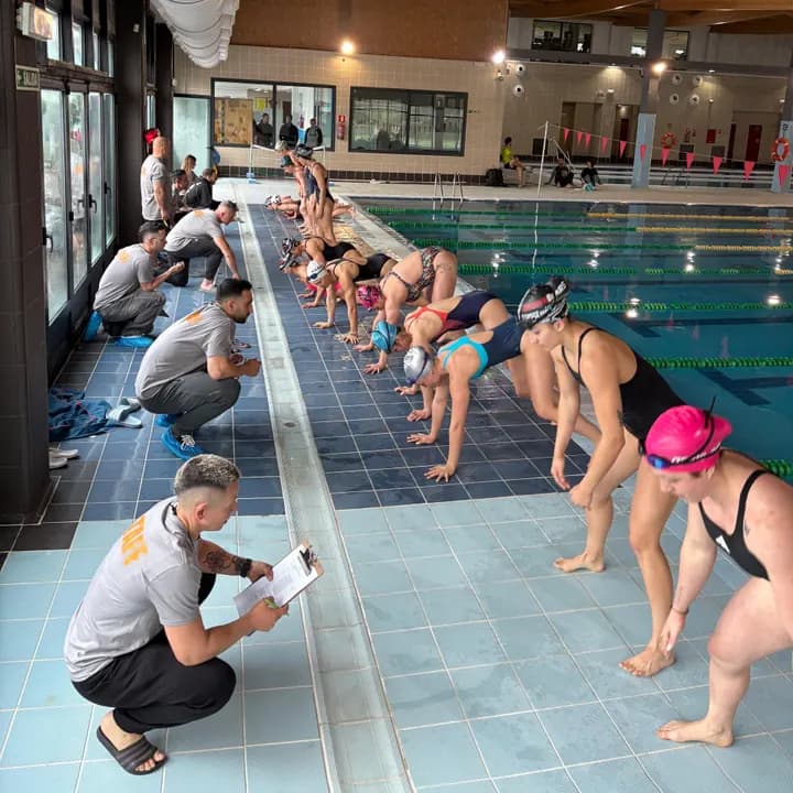 Atletas en el borde de la piscina, listas para la salida, ante los jueces