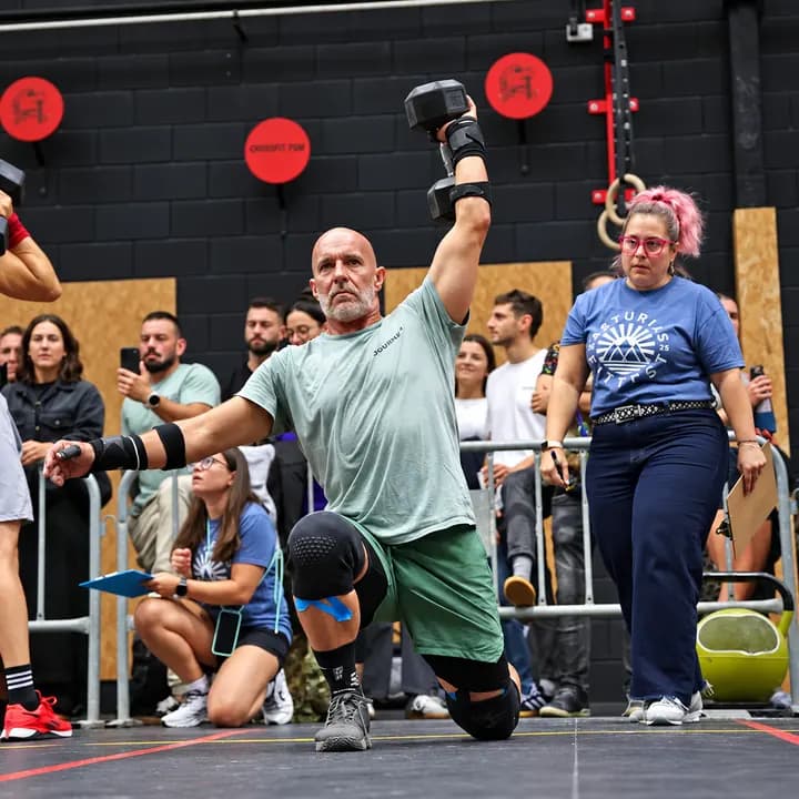 Atleta con mancuerna ante la mirada de una jueza